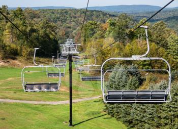 View down the valley with many empty ski chairlifts on a bright autumn fall day