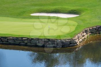 Flag and hole on a luxury golf course with water hazard and sand trap surrounding the green