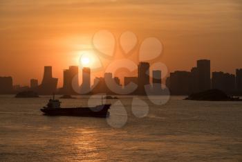 Cargo ship sails at sunset into port of Xiamen in China
