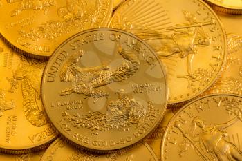 Pile of golden coins with Gold Eagle on US Treasury issue one ounce pure gold coin