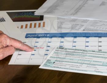 Senior hand holding Form 1040 Simplified for 2018  which allows for filing on April 15, tax day, on a postcard