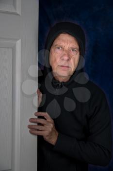 Senior retired caucasian man entering a home through doorway with worried expression