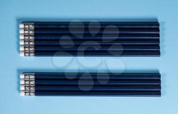 Row of new blue pencils lined up with erasers side by side. Copy space for back to school message