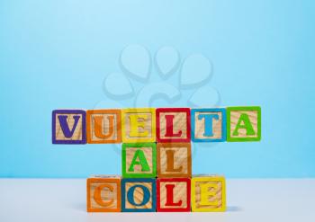 Vuelta al Cole translates to Back to School in spanish with wooden blocksagainst blue background with copy space
