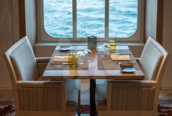 Romantic dinner setting for couple or two people by window on cruise ship restaurant