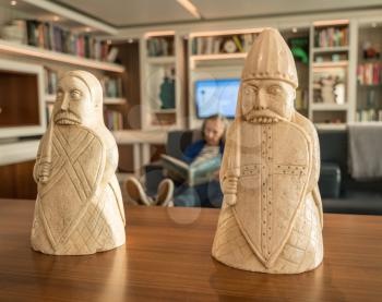 Woman relaxing and reading a book in a study fronted by Lewis Chessmen models
