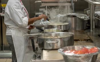 Chef preparing food  in commercial stainless steel kitchen in restaurant
