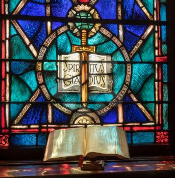 Colored light from stained glass window in methodist church falls across open bible