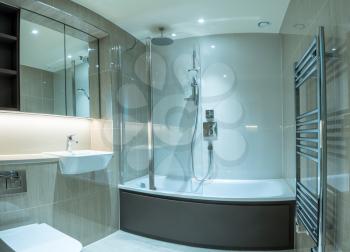 Modern clean bathroom in flat or apartment with bath shower, towel rail, sink and mirror cabinets