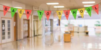 Colorful sack cloth pennants to create pennant flag message of Back to School above entrance of school corridor