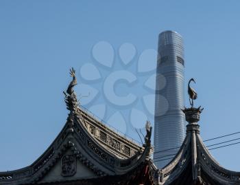 Detail of roof carvings with modern tower block in Yuyuan Garden in  the old city of Shanghai