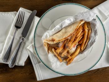 From above view of wrapped chicken souvlaki gryo takeout food plated at home with napkin