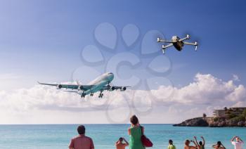 Conceptual composite of modern drone taking photos of International jet plane landing at airport on Caribbean island of St Martin