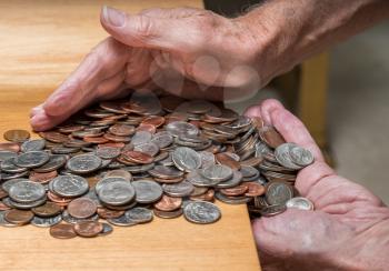 Hundreds of US coins being gathered into hands on wooden table as concept for hoarding during shortage of loose change