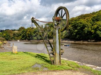 Rusty old metal winch or crane for cargo by the tidal River Tamar at Cotehele in Devon