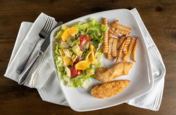 From above view of home made salad, chips and chicken tenders or nuggets plated at home with napkin