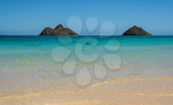 Lone swimmer on Lanakai Beach with Moku Nui and Moku Iki islands in the background