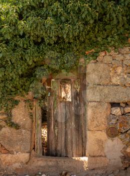 Wooden door opening into garden of stone house in the ancient town of Castelo Rodrigo in Portugal