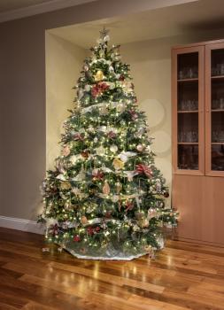 Carefully and beautifully decorated xmas tree in the corner of a modern home with wooden floors