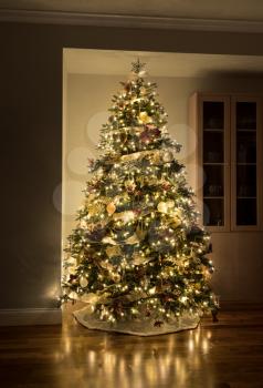 Carefully and beautifully decorated xmas tree in the corner of a modern home with wooden floors