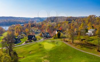 Aerial drone panorama of single family houses set among golf fairway and greens by a lake in autumn