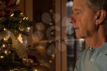 Senior adult man with christmas tree looking pensive and thoughtful as though remembering good times in the past
