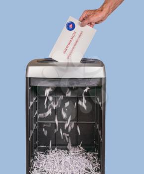 Vote by mail or absentee ballot being shredded in office paper shredder as illustration of voting fraud or lost votes in Presidential election