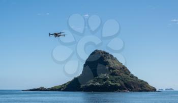 Modern drone flying in the air in front of Chinaman's rock or Mokoli'i off the coast of Oahu, Hawaii