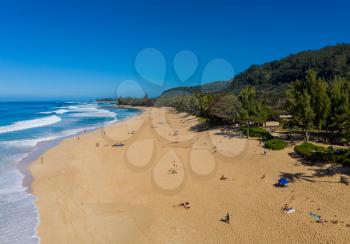Locals and tourists on the sand beach at Banzai Pipeline on north coast of Oahu, Hawaii