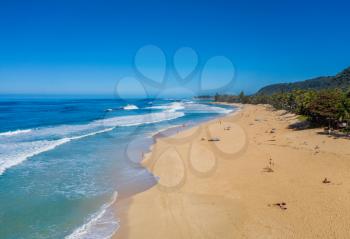 Locals and tourists on the sand beach at Banzai Pipeline on north coast of Oahu, Hawaii