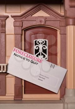 Envelope being served at toy dollhouse containing a foreclosure notice due to failure to pay rent on the property