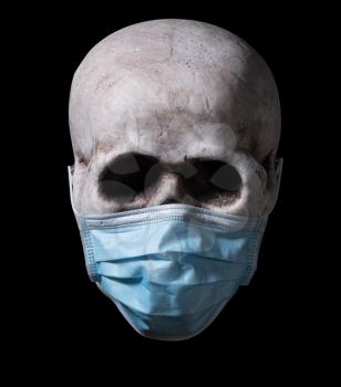 Human skull with a medical face mask isolated against a black background. Halloween image for the coronavirus pandemic era.