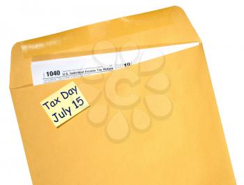 Printed Form 1040 for income tax return in brown envelope with reminder for July 15 tax day due to Covid-19 virus delay
