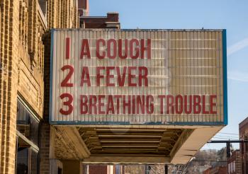 Cinema billboard with three main symptoms or signs of a coronavirus or Covid-19 infection of coughing, feverish and trouble with breathing