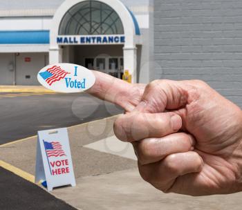 USA flag campaign button stuck to finger of voter by Polling place for early voting in the USA presidential elections