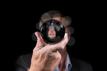Senior caucasian hand holding glass sphere with upside down reflection of head. Concept for fear of change, new reality or world upside down