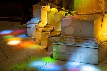 Colored lights from stained glass windows on columns inside the Batalha Monastery near Leiria in Portugal