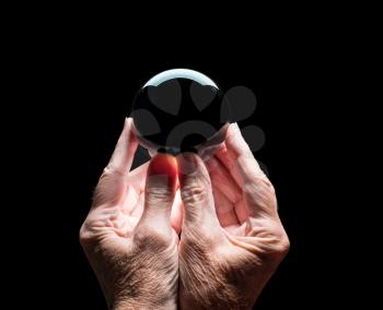 Senior caucasian hands holding a crystal futures or fortune telling ball with black center to allow compositing of your logo