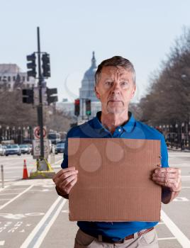 Senior caucasian man holding a blank cardboard sign for copy space message. He is composited into Washington DC street scene