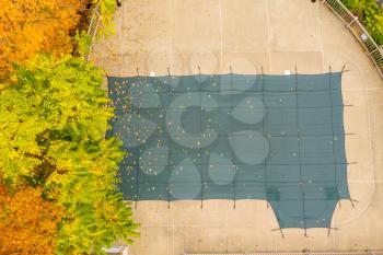 Aerial drone point of view of a green plastic cover on HOA swimming pool protecting it from leaves and for the winter storms