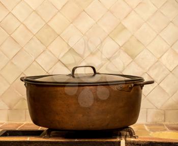 Side view of an old copper cooking pan or casserole pot on kitchen counter