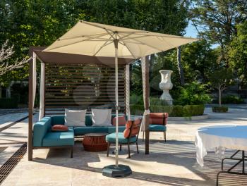 Modern outdoor furniture with umbrella on paved marble patio or courtyard