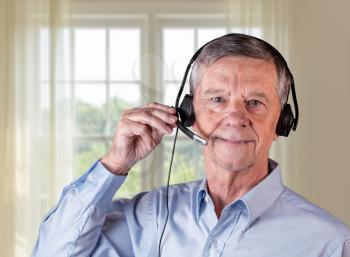 Senior caucasian man using headset to talk to customers or team in work from home.