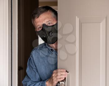 Concerned and worried man wearing a protective breathing mask against flu and coronavirus and greeting visitor
