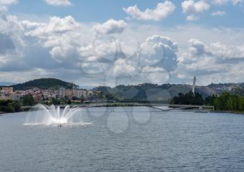 River based fountain and modern suspension bridge over the Mondego river in Coimbra