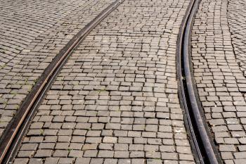 Curve of steel rails from tramcar track set into stone cobble pattern in Porto