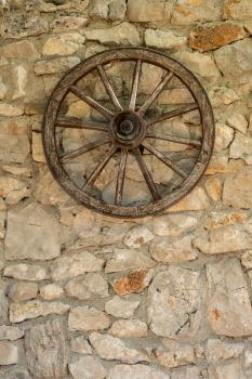 Old wooden cart wheel on stone farmhouse wall