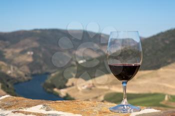 Glass of red wine or port for tasting above the hillsides of the Douro valley in Portugal