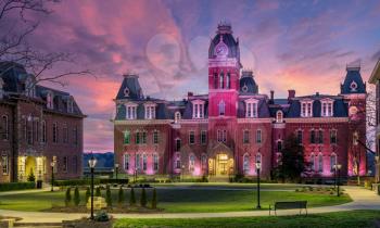 Dramatic image of Woodburn Hall at West Virginia University or WVU in Morgantown WV as the sun sets behind the illuminated historic building