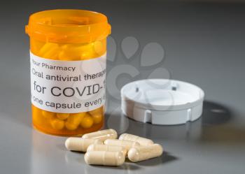 Prescription bottle and capsules illustrating trials of oral antiviral treatment for SARS-CoV-2 or Covid-19 virus